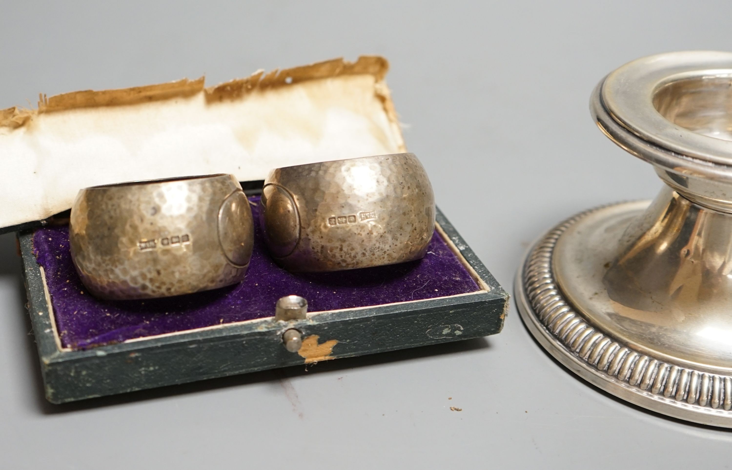 A German white metal dwarf candlestick and a cased pair of silver napkin rings by Walker & Hall.